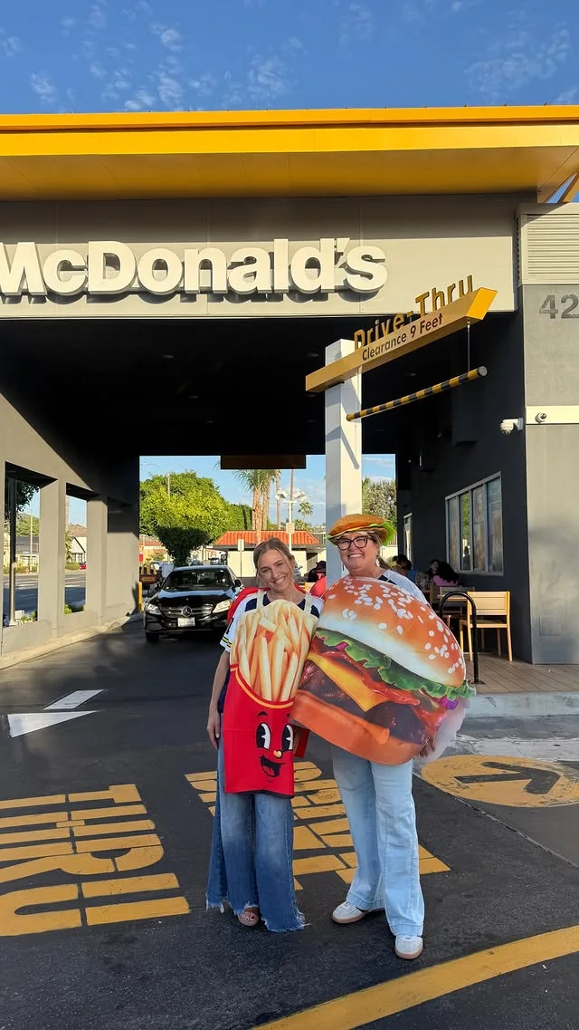 Two people in french fry and hamburger costumes outside McDonald’s