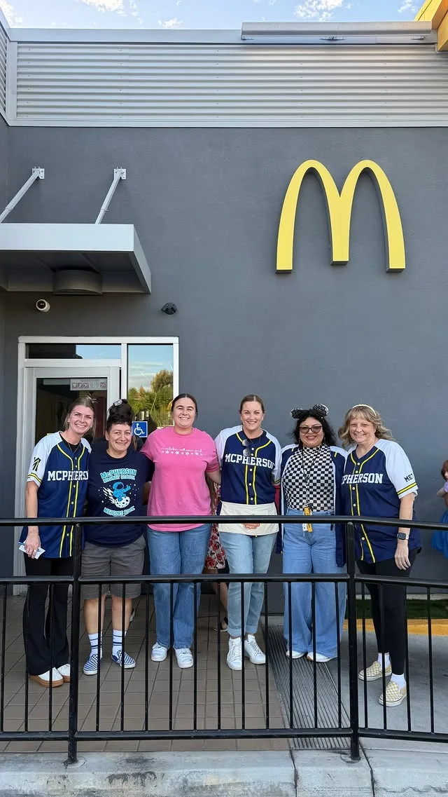 A group posing outside McDonald’s, several wearing McPherson shirts