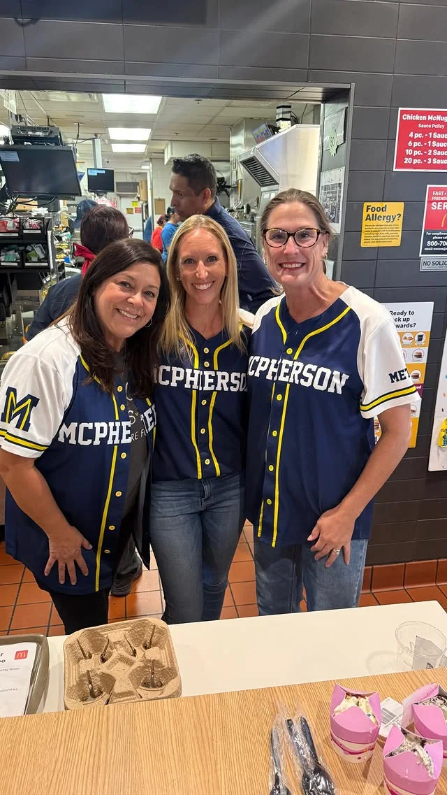 Three people in blue and yellow McPherson shirts inside McDonald’s