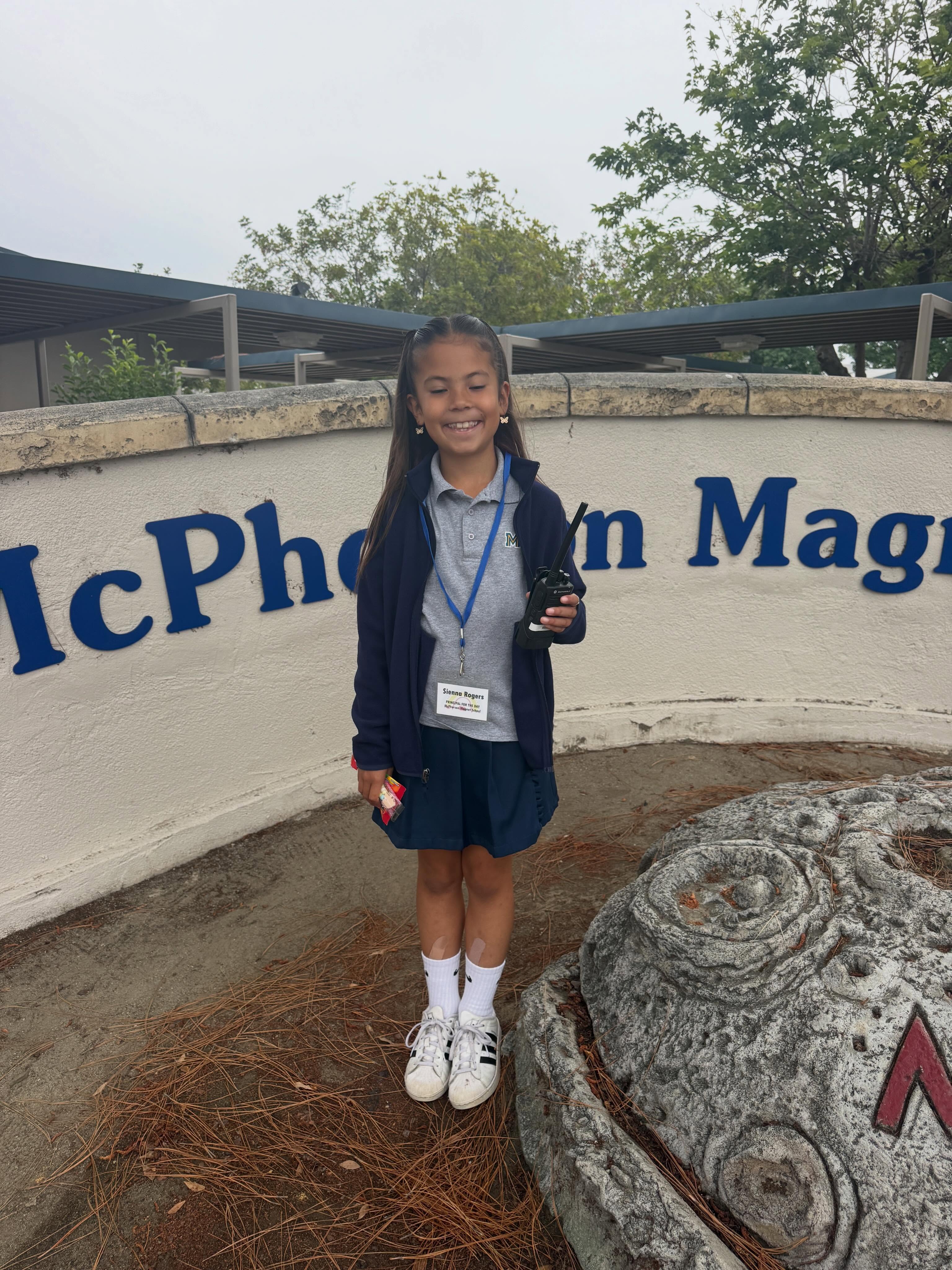 A McPherson elementary student serving as Principal for the Day beside the school sign