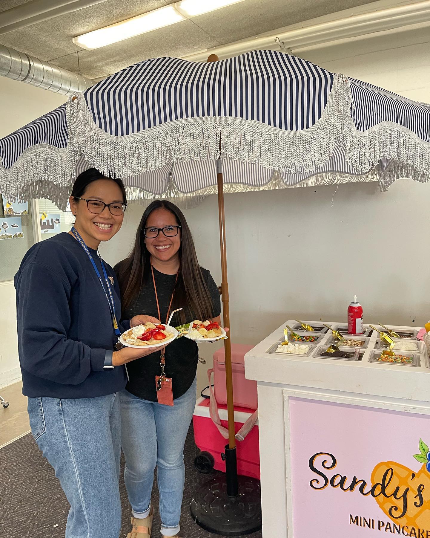 Two McPherson staff members smiling with plates of pancakes during Teacher Appreciation Week